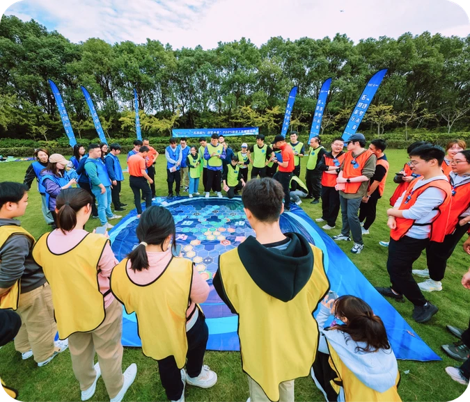 二三四五员工在草地上围圈参与团队游戏